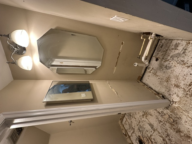 Bathroom stripped to damaged walls and old mirrors