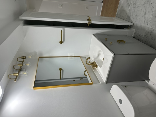 Finished bathroom vanity with gold-framed mirror and brass fixtures